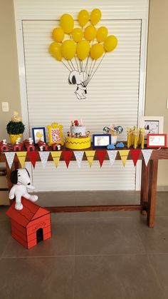 a birthday party with balloons and decorations on the wall, including a doghouse cake table