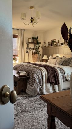 a bedroom with a large bed and two lamps hanging from the ceiling over it's headboard