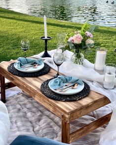 the table is set with plates, silverware and candles on it for an outdoor dinner