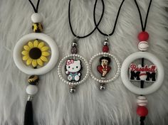 three necklaces with hello kitty charms hanging on a white furnishing area next to a black tassel