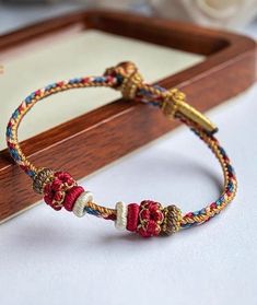 the bracelet is decorated with red, white and blue beads on a wooden box next to flowers