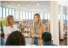 two women and one man are talking to each other in a library with bookshelves