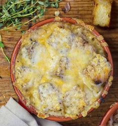 two red bowls filled with cheese and bread on top of a wooden table next to small pieces of bread