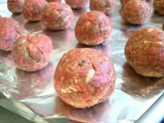 raw meatballs are sitting on a sheet of aluminum foil and ready to be cooked