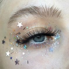 a close up of a person's eye with stars all over the eyes and eyelashes