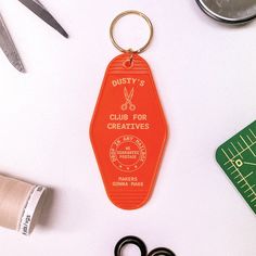 an orange keychain sitting on top of a table next to scissors and thread