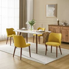 a dining room table with yellow chairs and a white rug on the floor in front of it