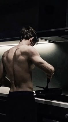 a shirtless man is cooking in the kitchen