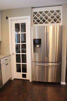 a stainless steel refrigerator and freezer combo in a kitchen with white cabinets, wood flooring and hardwood floors