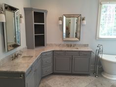 a large bathroom with marble counter tops and gray cabinets, along with a claw foot tub