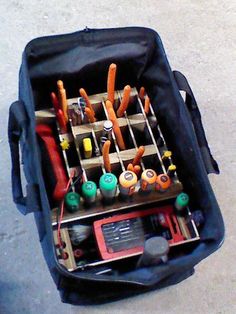 an open tool bag filled with tools on the ground