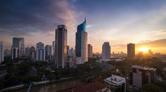 the sun is setting behind some tall buildings