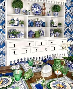 a dining room table with blue and white dishes on it, plates and vases