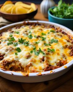 a casserole dish with cheese and meat in it on a cutting board next to other dishes