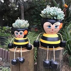 two wooden bees with succulents on their heads sitting on top of logs