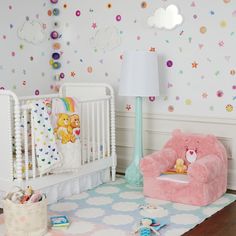 a baby's room with a crib, teddy bear and other items on the floor