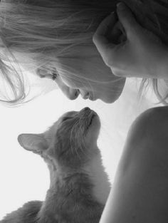 a woman holding a kitten in her arms and looking up at it's face