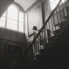 a person walking up some stairs in an old building with sunlight coming through the windows