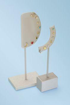 a pair of earrings are on display in front of a blue background with a white stand