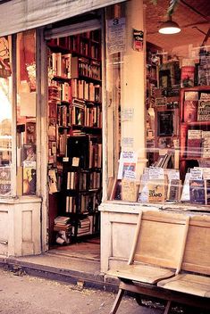 an old book store with many books on the shelves and two wooden benches in front