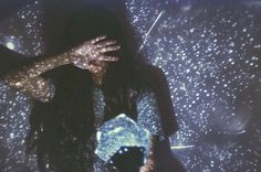 a woman standing in the rain with her hands on her face and holding an umbrella