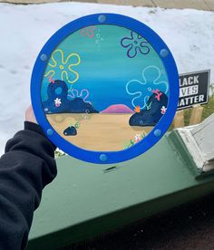 a person holding up a painted plate with an octopus and sea life scene on it