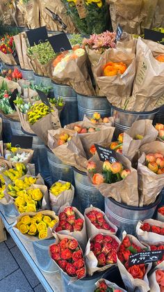 many different types of flowers in buckets on display at a flower shop with price tags