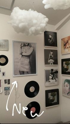 there are many pictures on the wall with clouds in the sky above them and vinyl records hanging from the ceiling