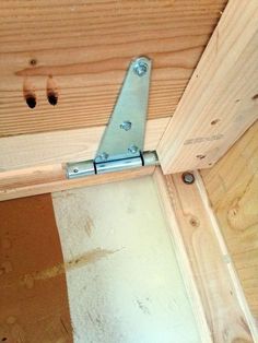 a metal hinge is attached to the side of a wooden structure with screws