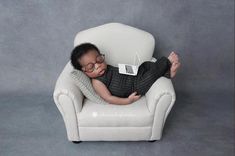 a baby wearing glasses is laying in a chair with a laptop on it's lap