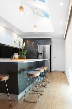 a kitchen with an island and stools in the center, along with a skylight