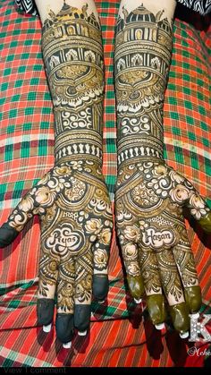 two hands that are decorated with henna and green beads on top of a bed