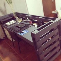 a desk made out of pallet crates with a plant in the middle and other items on top