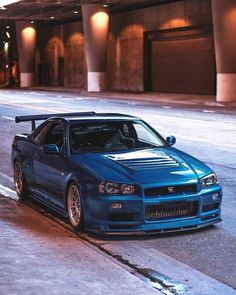 a blue car parked on the side of a road next to a building at night