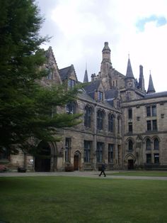 a person walking in front of a large building with many windows and towers on it