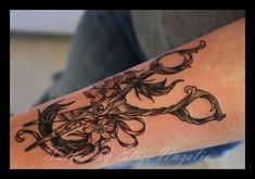 a tattoo on the arm of a person with scissors and flowers in their hair,