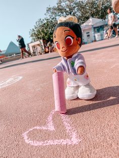 a stuffed doll sitting on the ground next to a pink marker