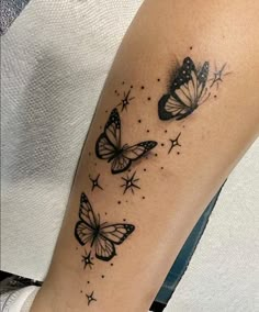 a woman's arm with three butterflies on it and stars in the sky above