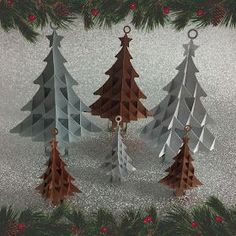 three christmas trees are hanging from a tree branch