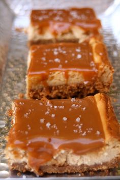 two pieces of caramel cheesecake sitting on top of a glass plate covered in frosting