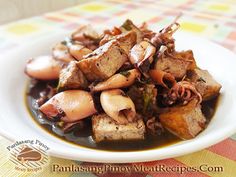 a white plate topped with tofu and mushrooms on top of a colorful table cloth