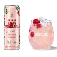 a can of absolut berry vodka next to a glass filled with ice and raspberries