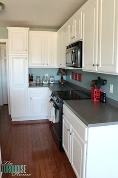 a kitchen with white cabinets and black counter tops is pictured in this image from the front view