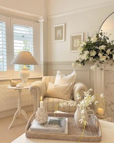 a living room filled with furniture and flowers on top of a table in front of a window