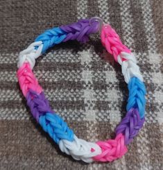 a close up of a colorful bracelet on a bed with a checkered table cloth