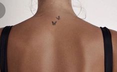 the back of a woman's neck with a small butterfly tattoo on her left side