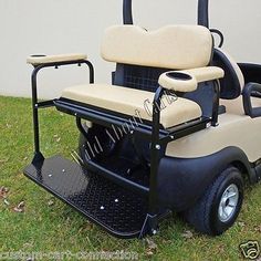 a golf cart sitting in the grass with its seat folded down on it's side