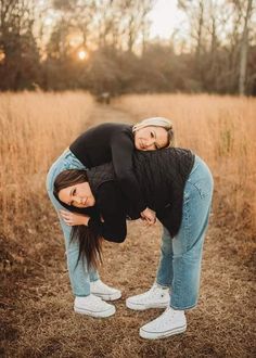 two women are standing in the middle of a field with their arms around each other