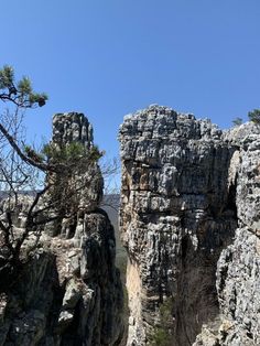 some very tall rocks and trees on a sunny day with blue sky in the background