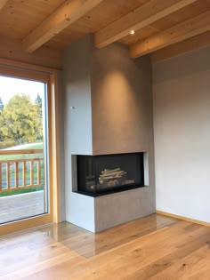 an empty room with a fire place in the center and wood floors on both sides